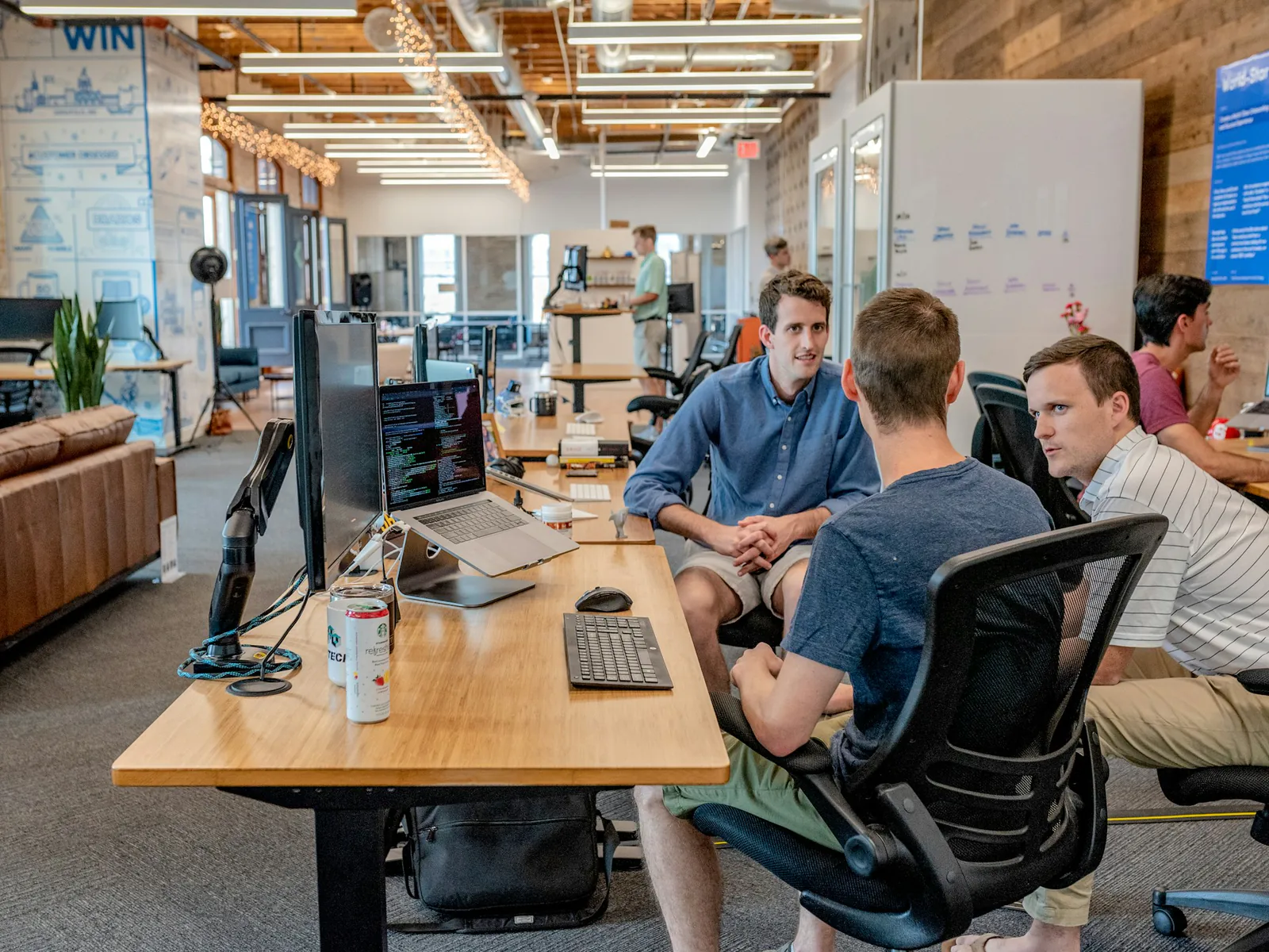 Team members discussing work around desks in a modern office